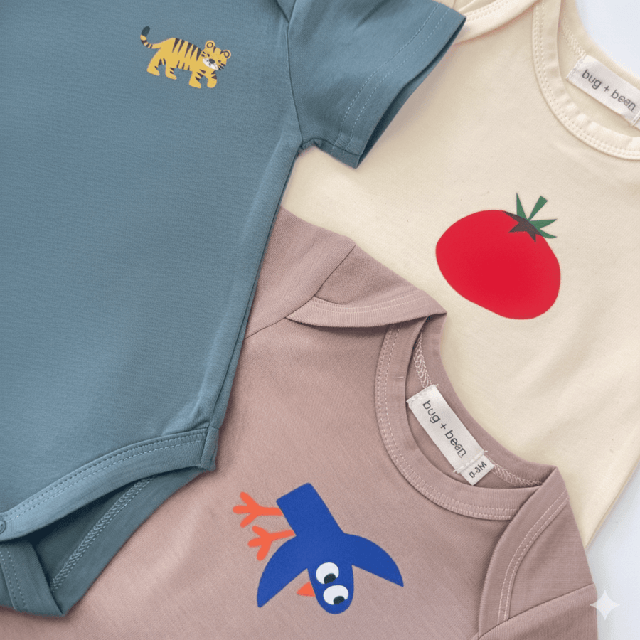 Three baby onesies with colorful designs on a light background